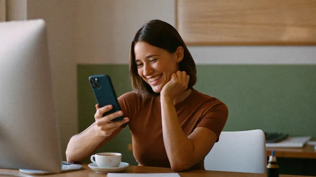 Geschäftsinhaberin liest lächelnd eine Nachricht auf ihrem Smartphone