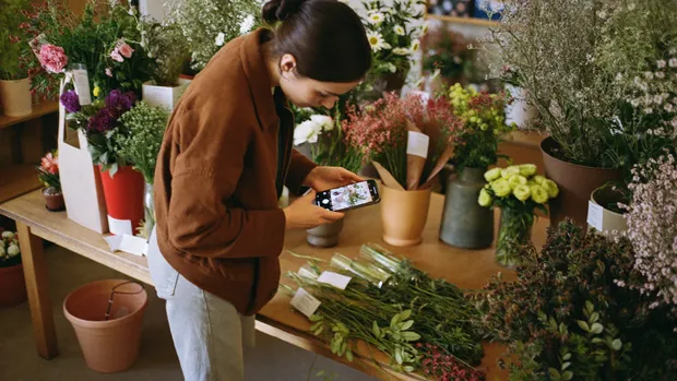Floristin fotografiert ihre Blumen und Produkte mit dem Smartphone für die Website
