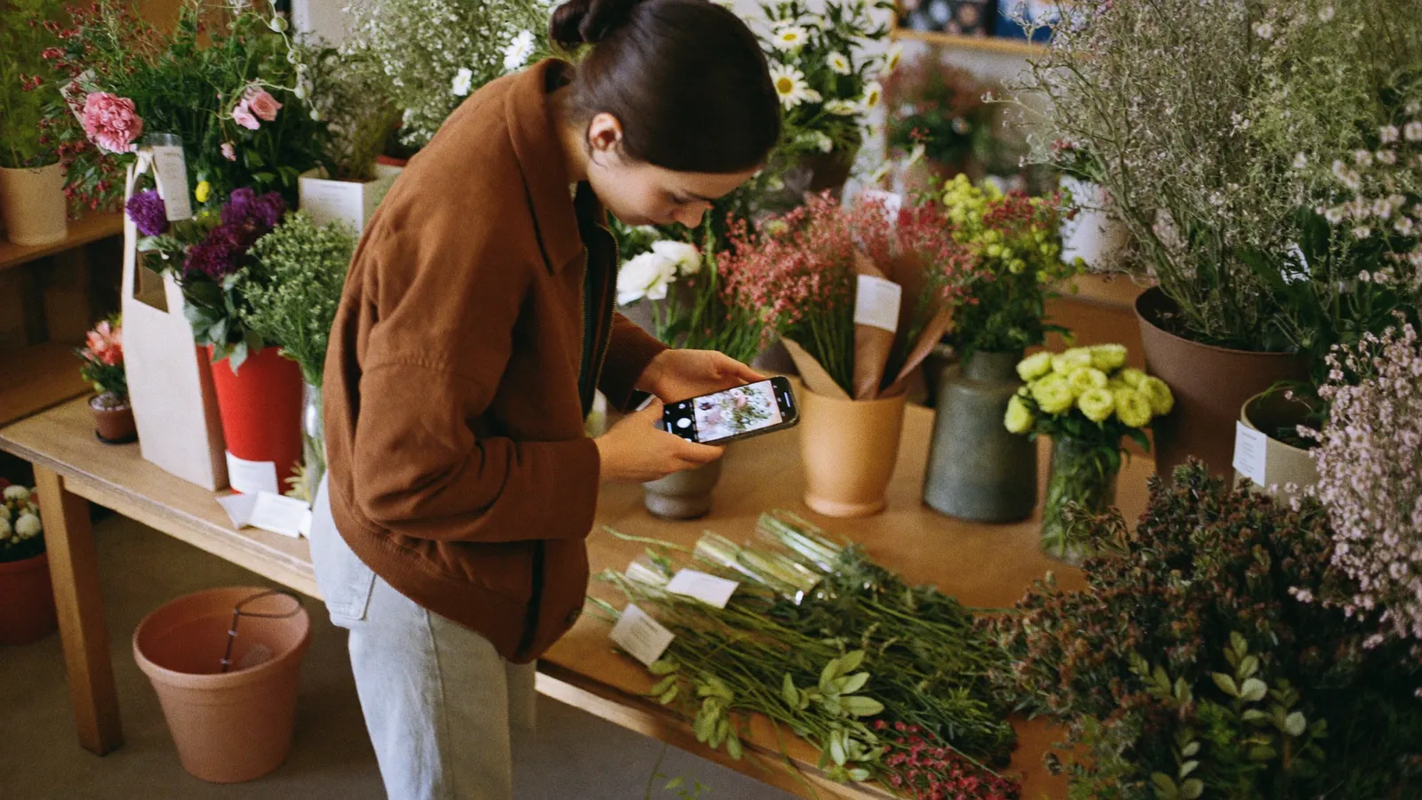Floristin fotografiert ihre Blumen und Produkte mit dem Smartphone für die Website