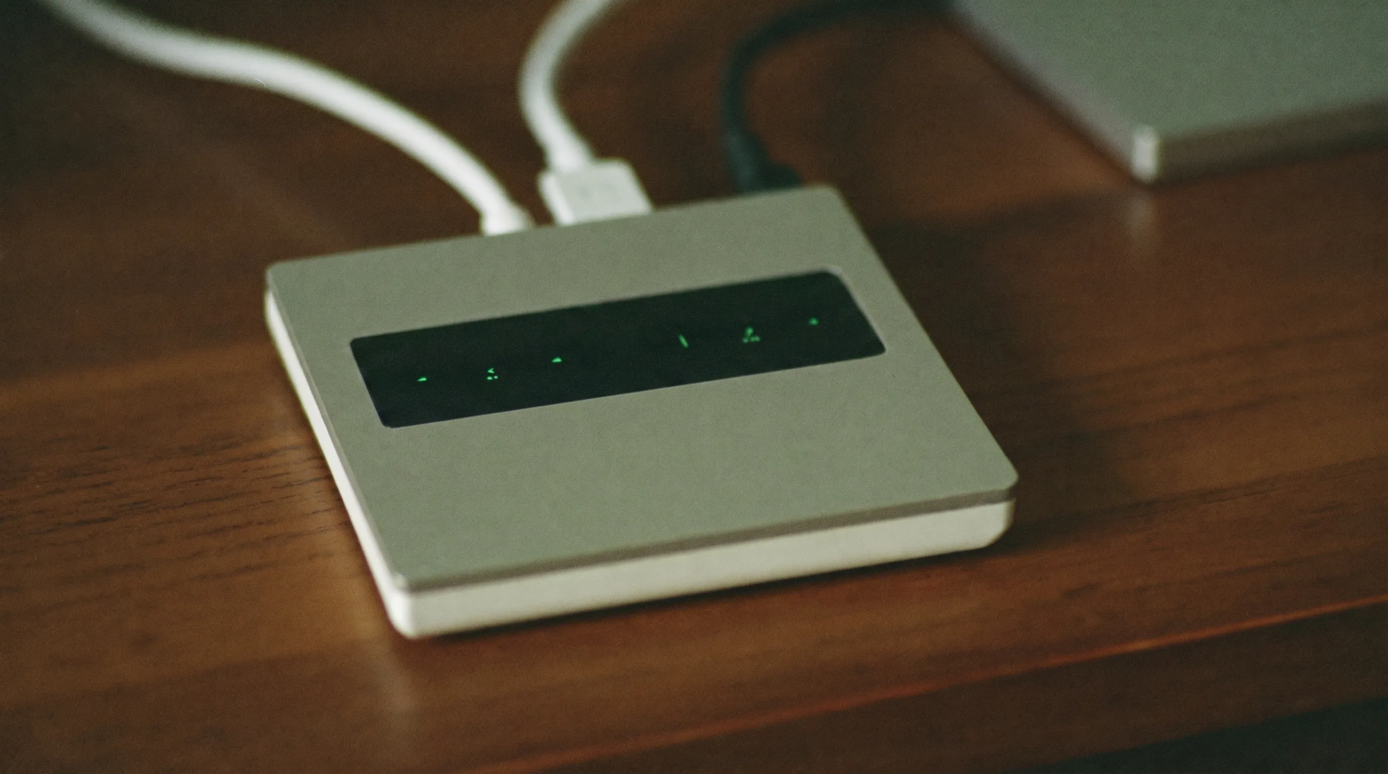 Kleiner Internet-Router mit Kabeln auf einem warmen Holzschreibtisch