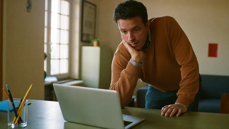 Unternehmer schaut etwas ratlos auf seinen Laptop im Homeoffice