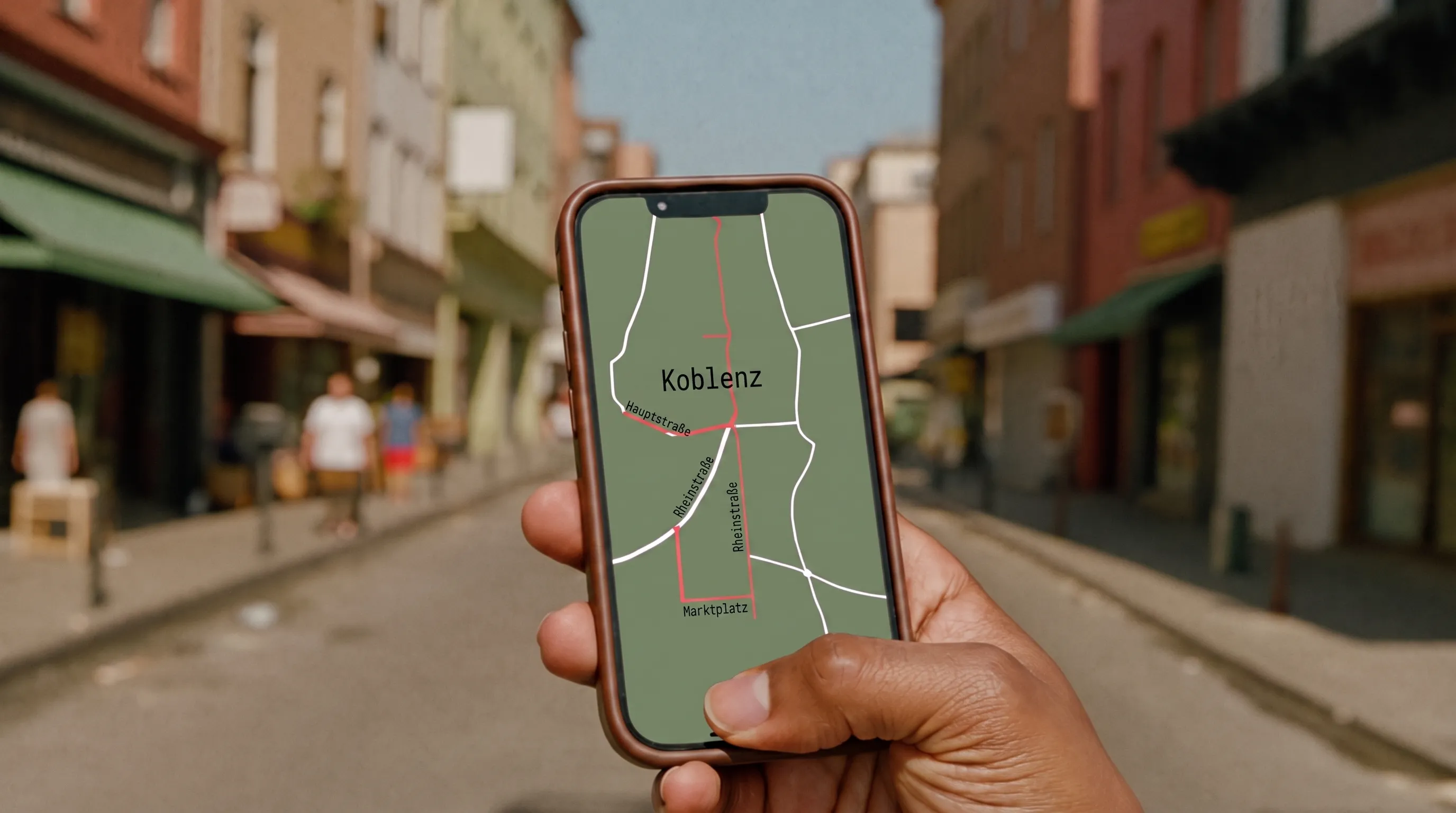 Hand hält ein Smartphone mit einer abstrakten Kartenansicht auf einer sonnigen Straße