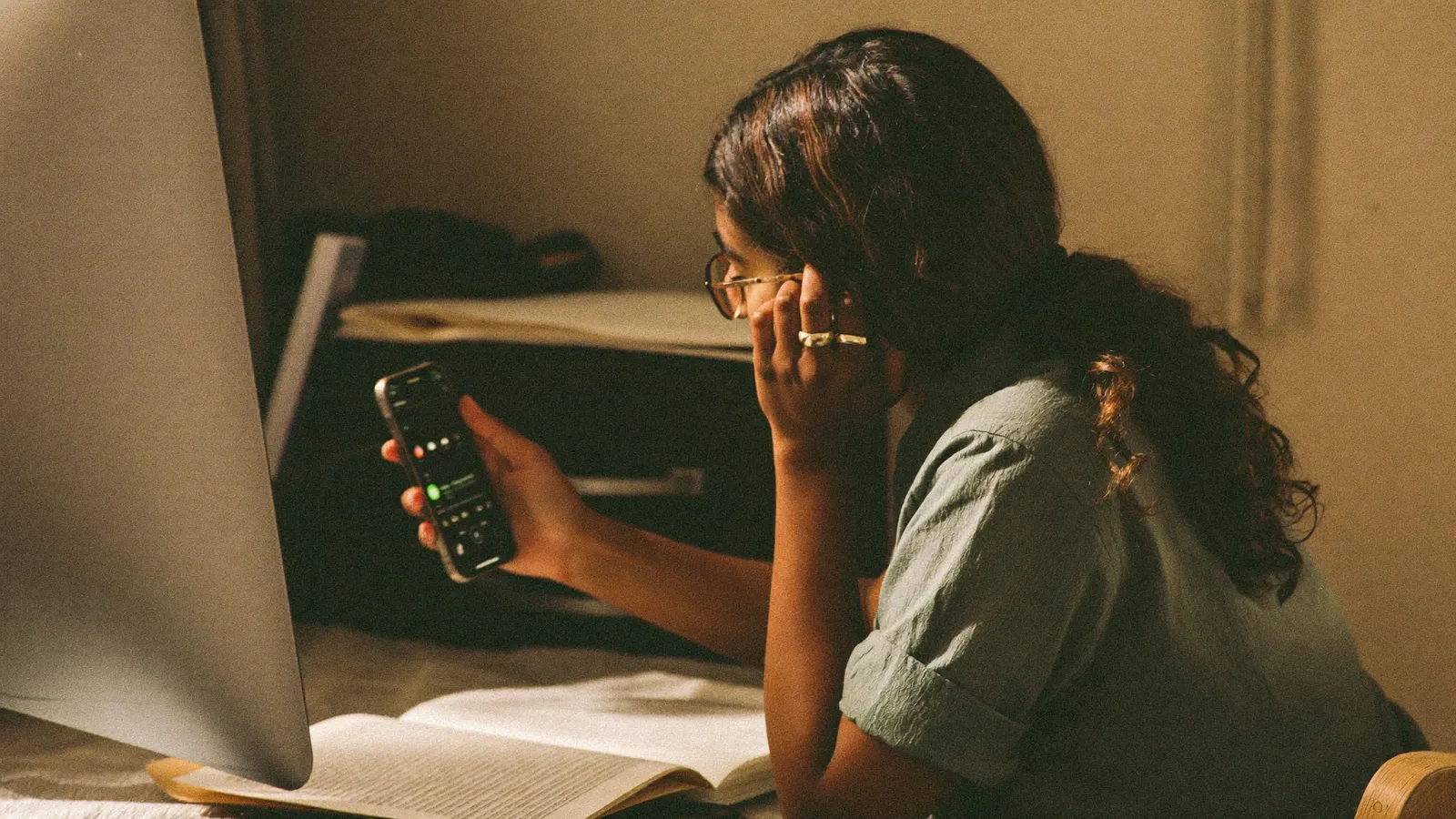 Unternehmerin sitzt nachdenklich mit dem Smartphone am Schreibtisch