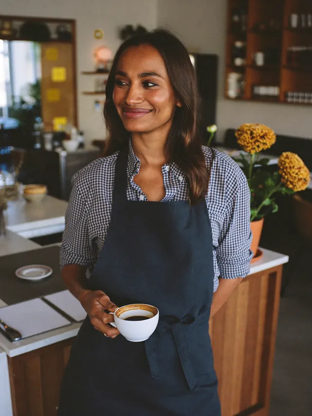 Gastronomin mit Kaffeetasse an der Theke ihres Cafés