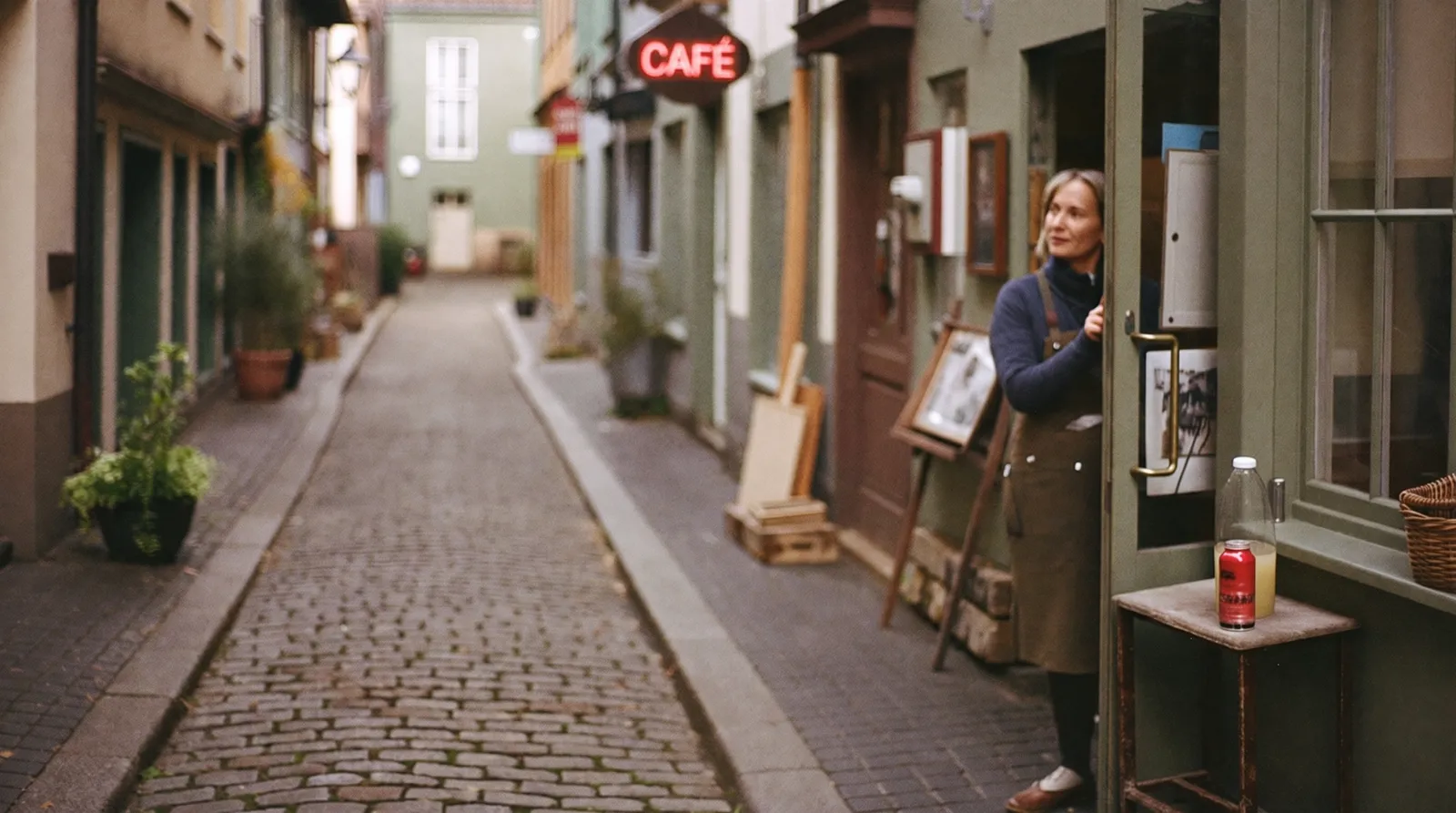 Handwerkerin in der Tür ihrer Werkstatt in einer Altstadtgasse
