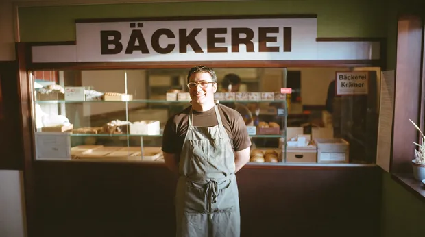 Freundlicher Bäckereiinhaber mit Schürze in seiner Backstube