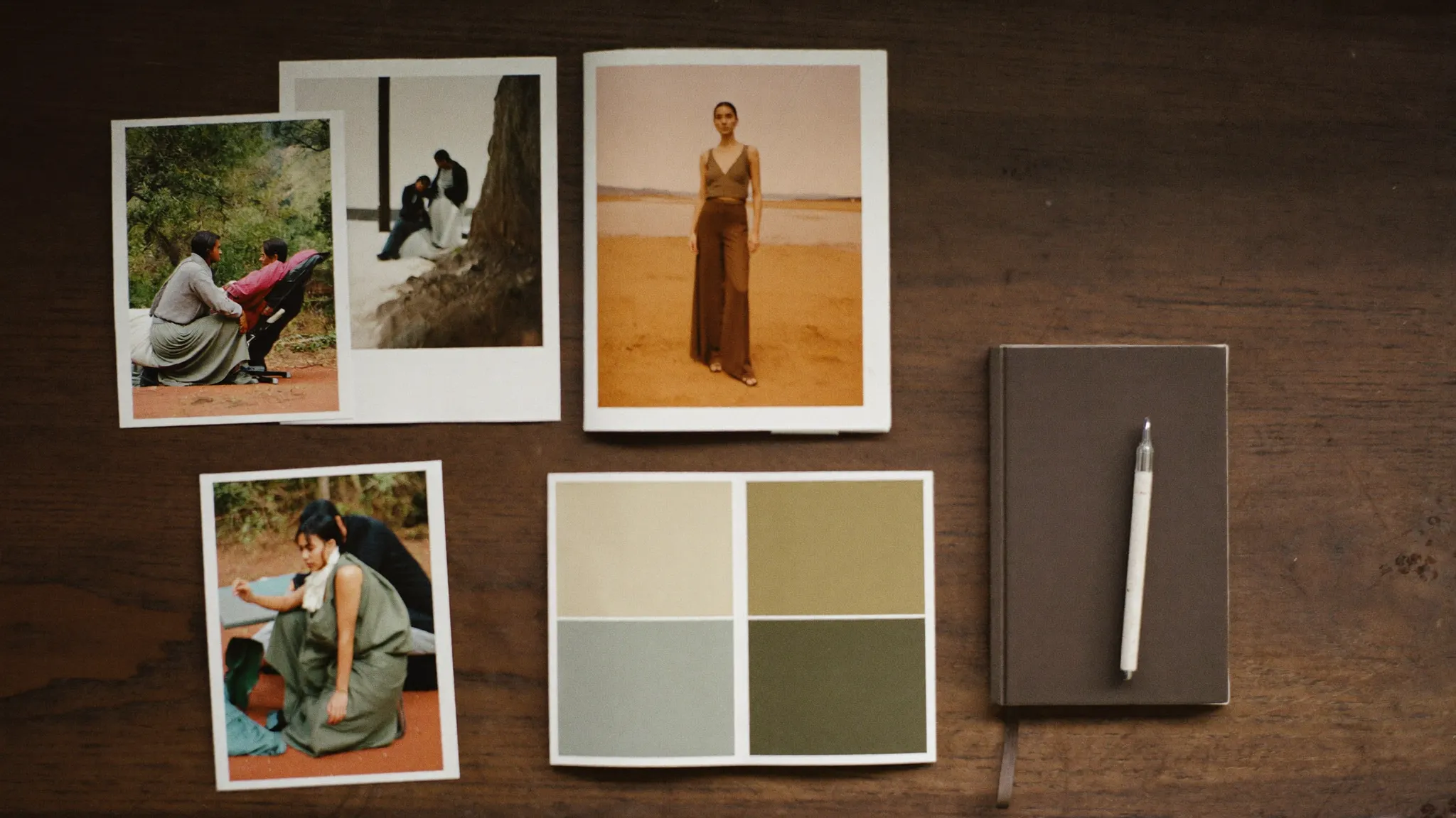 Aufsicht auf Projektmaterial: Fotos, Farbmuster, Notizbuch und Stift