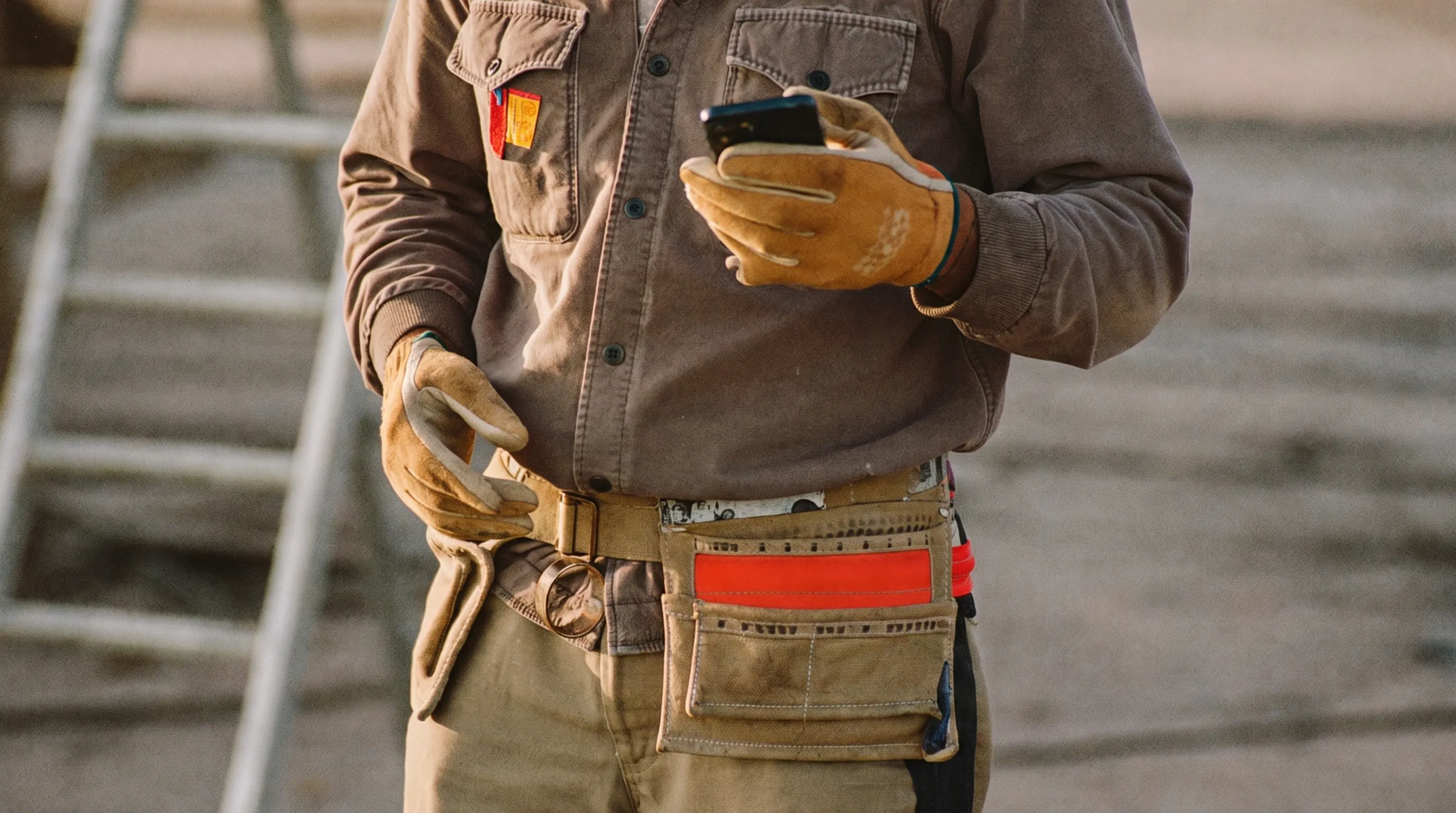 Handwerker auf der Baustelle schaut in einer Pause auf sein Smartphone